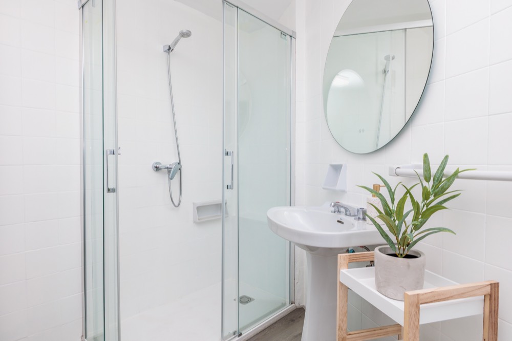 Baño compartido con ducha, lavabo y espejo redondo