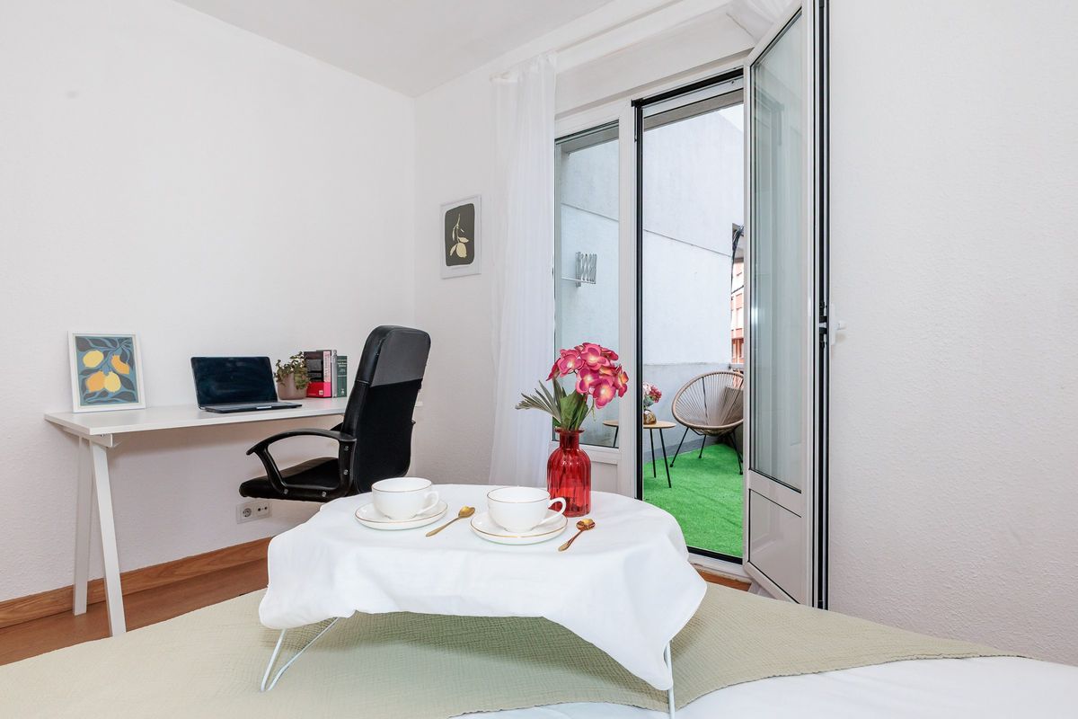 Habitación con escritorio, silla de oficina y salida a una terraza