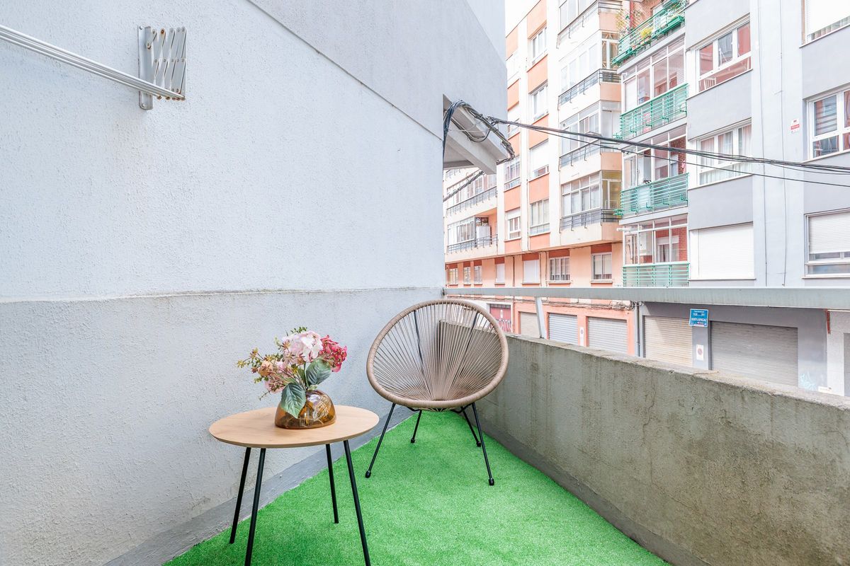 Terraza con césped artificial, silla colgante y mesita