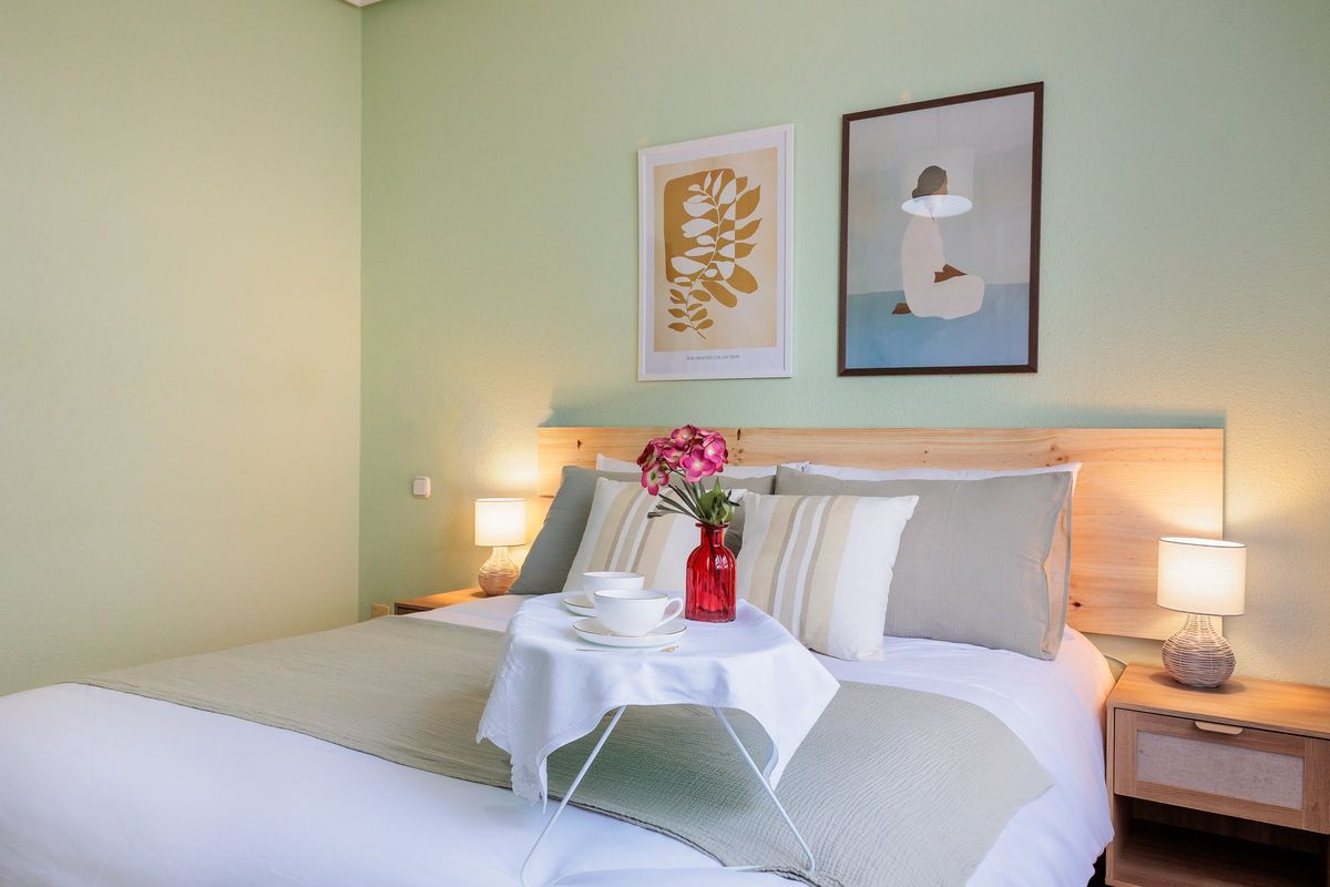 Cama de matrimonio con bandeja de desayuno y cuadros