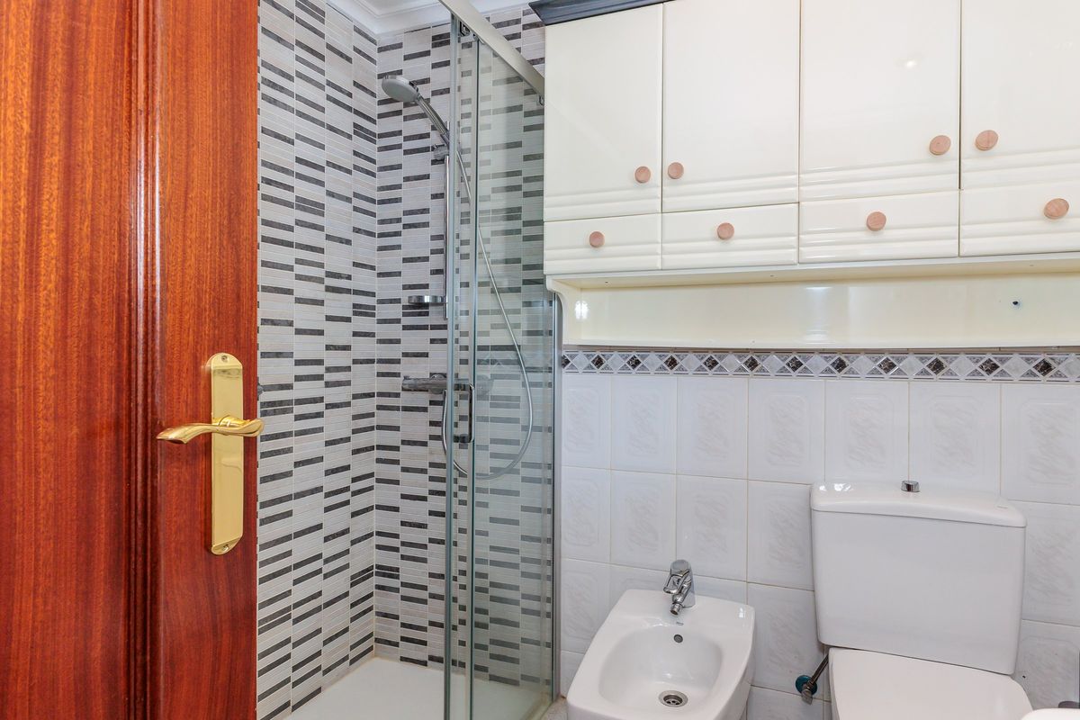 Baño con ducha de mampara y azulejo gris
